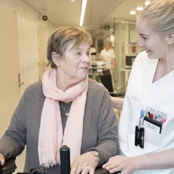 Sykepleier som smiler til eldre pasient