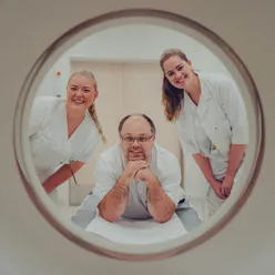 Tre radiologer som ser gjennom hullet til røntgenmaskinen