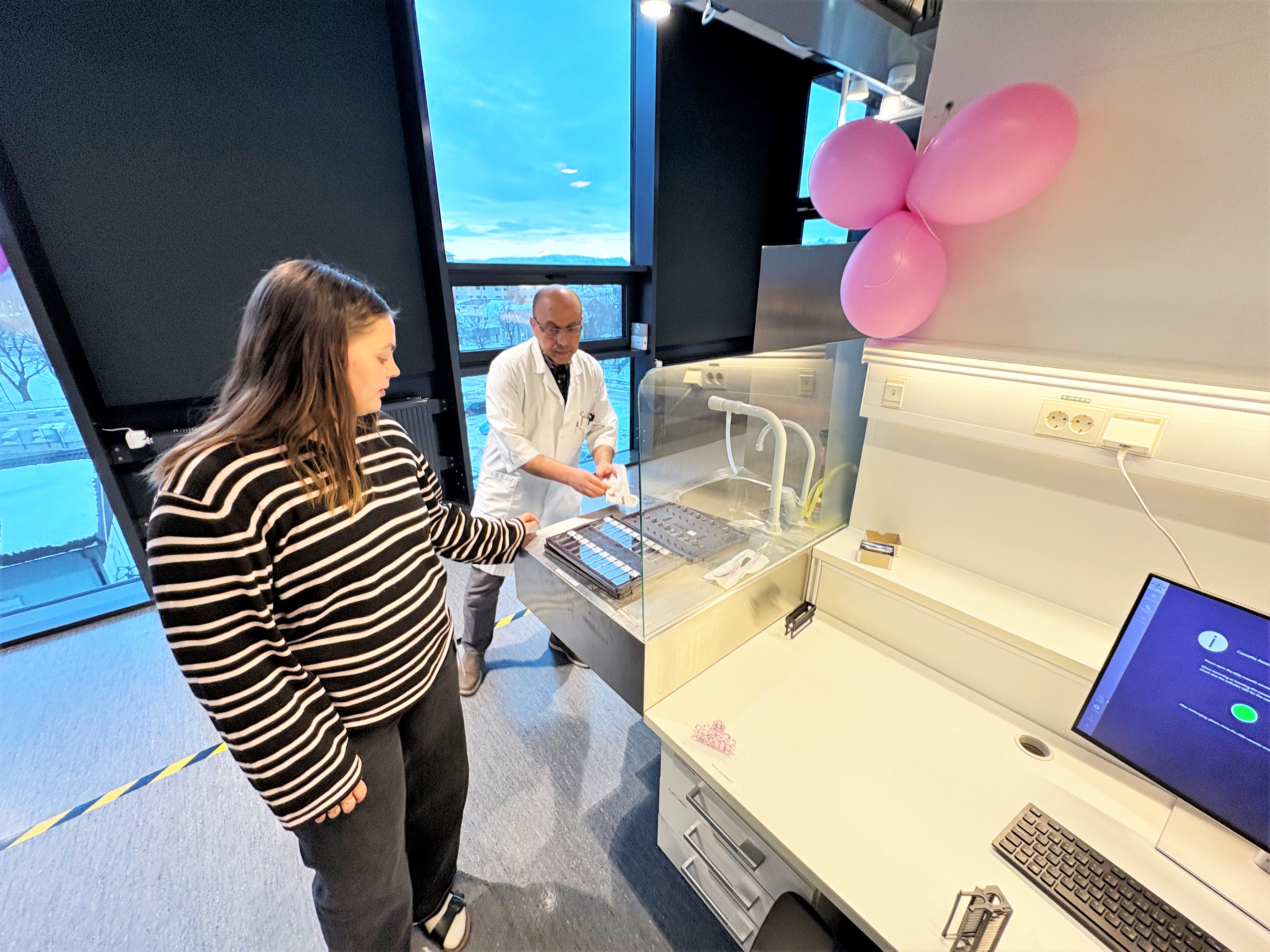 En mann og en kvinne står ved siden av en skjerm med datamaskiner