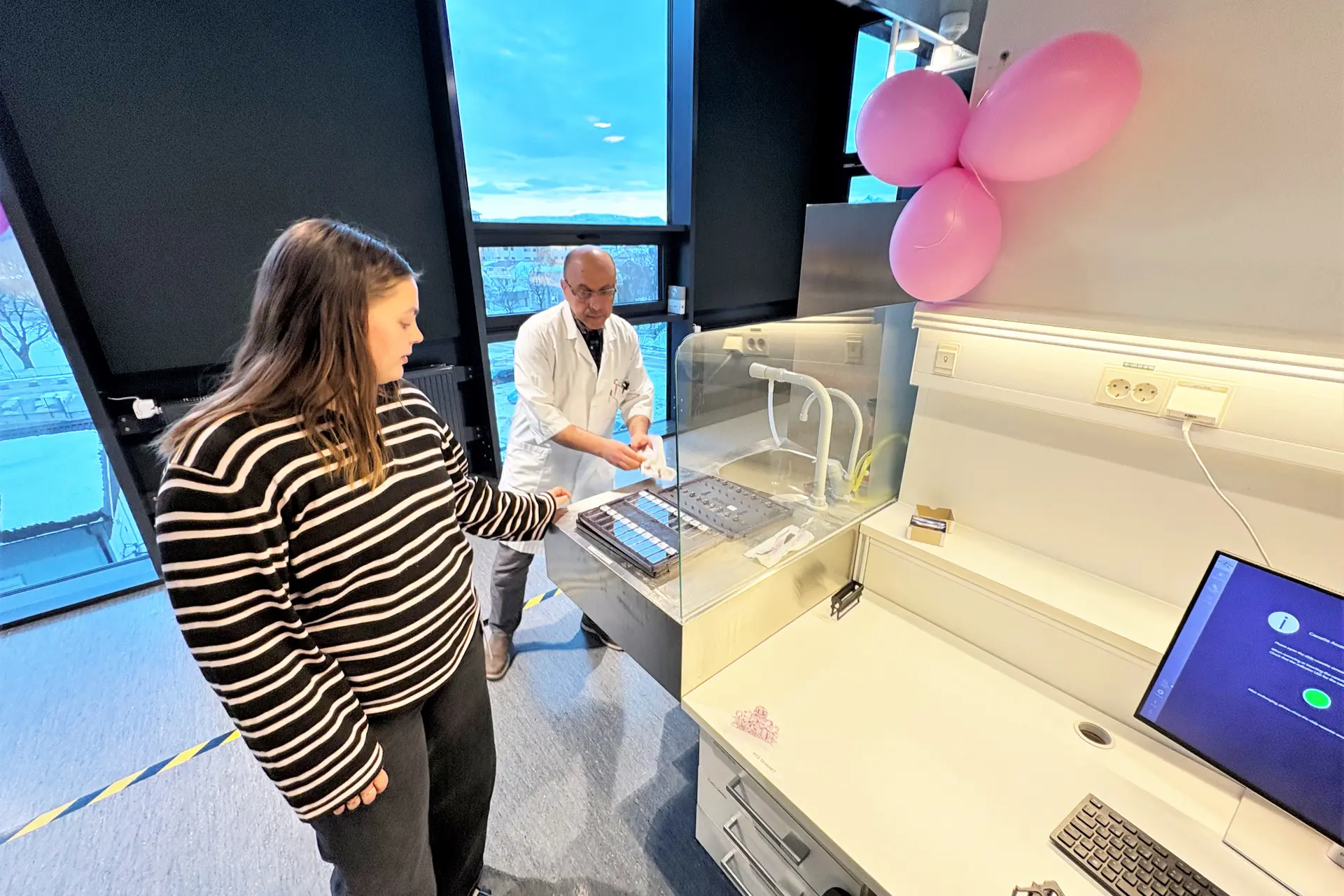 En mann og en kvinne står ved siden av en skjerm med datamaskiner