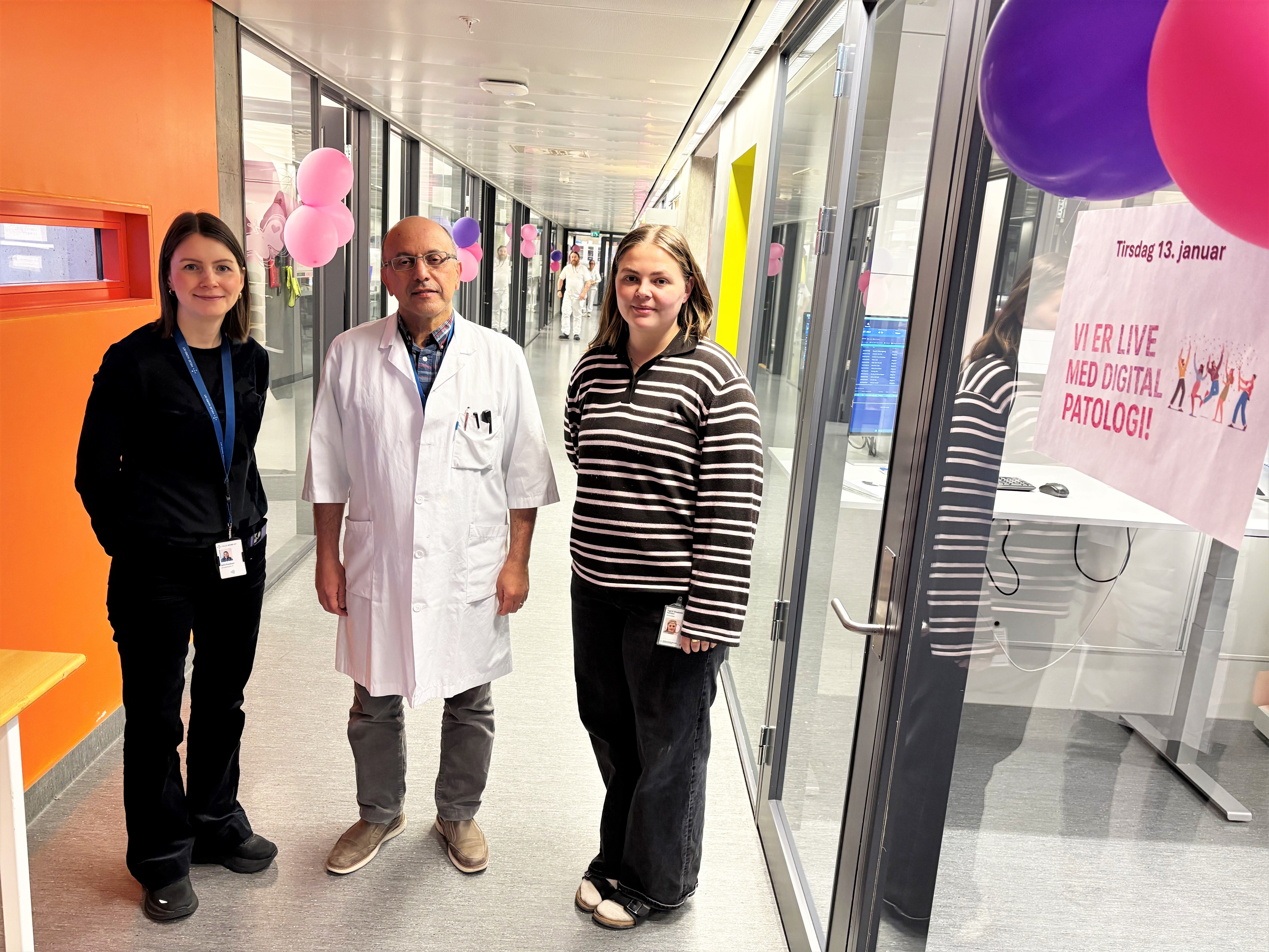 Tre personer står samlet i en korridor