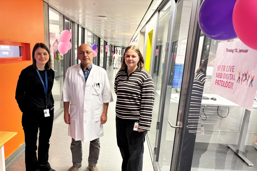 Tre personer står samlet i en korridor