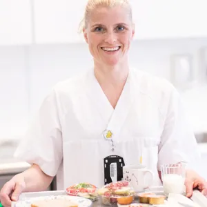 Kvinnelig sykepleier som holder matbrett
