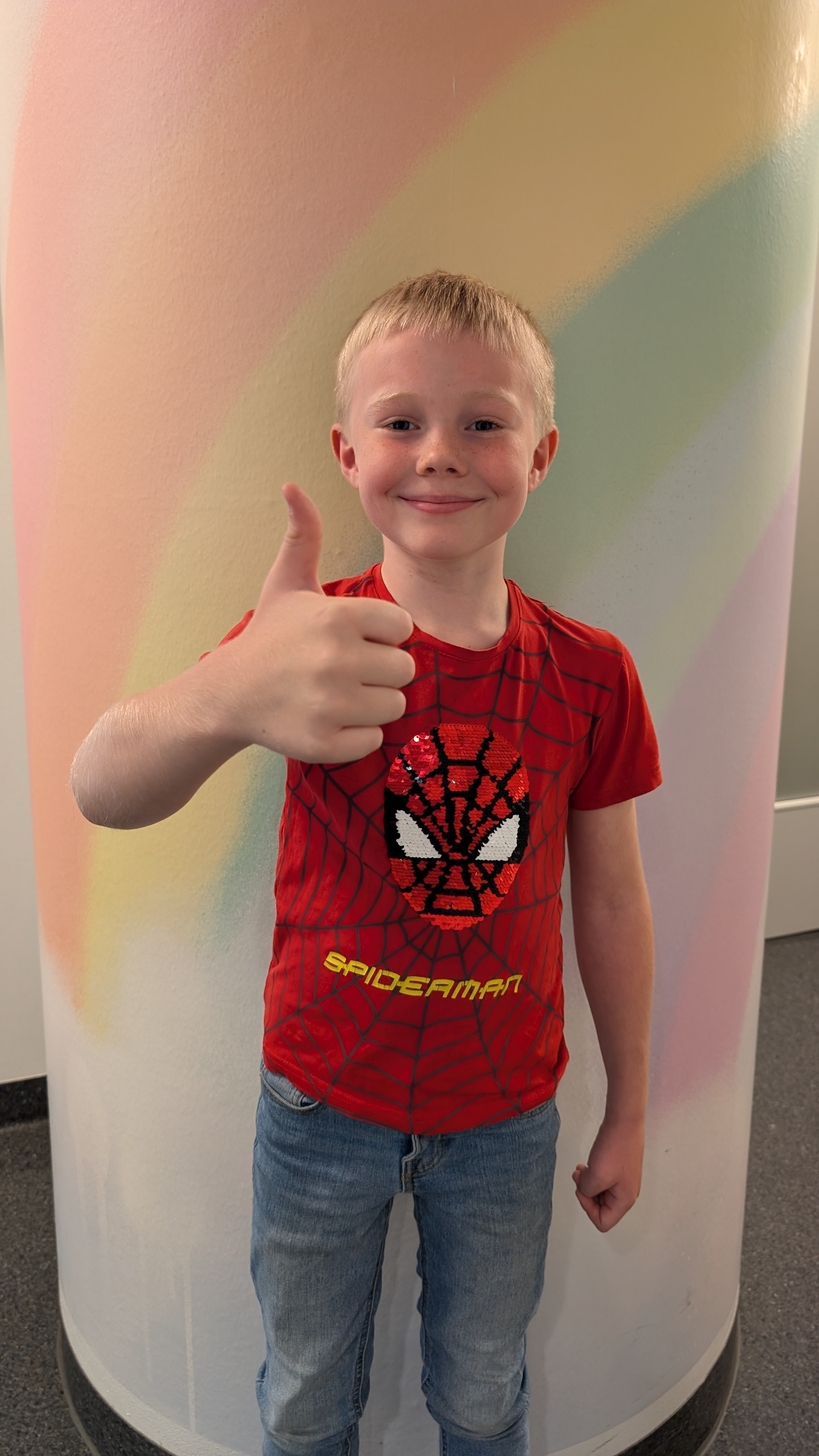 Gutt som smiler og holder tommelen opp