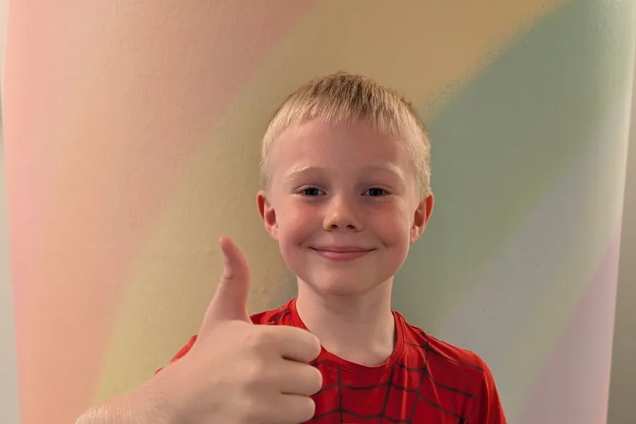 Gutt som smiler og holder tommelen opp