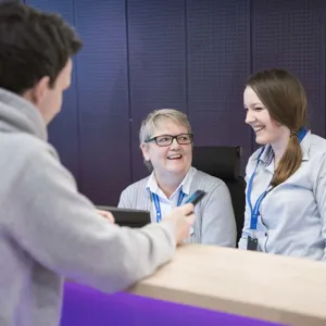 Ungdom som prater med to damer i en skranke