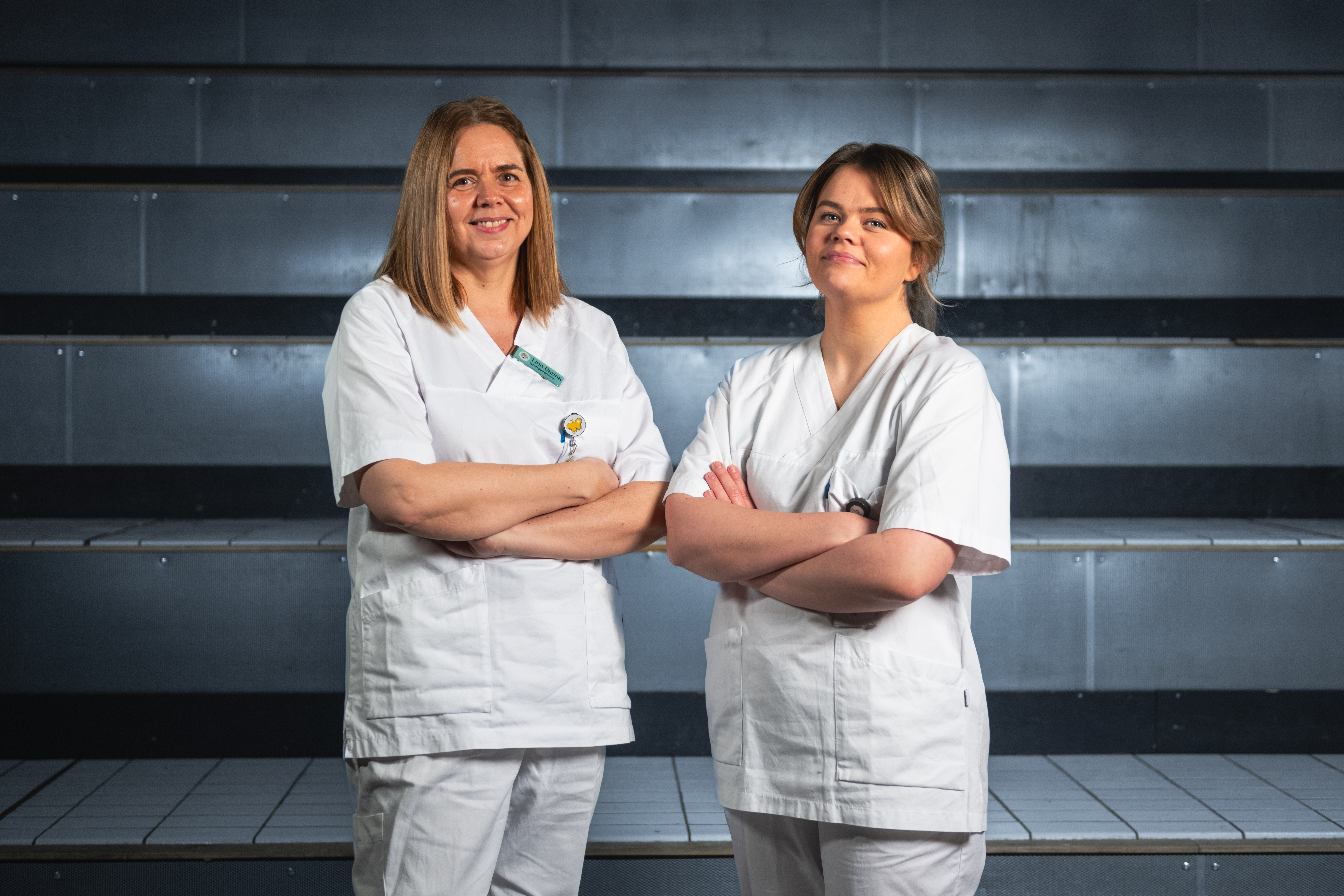 To damer som står samlet og smiler til kamera