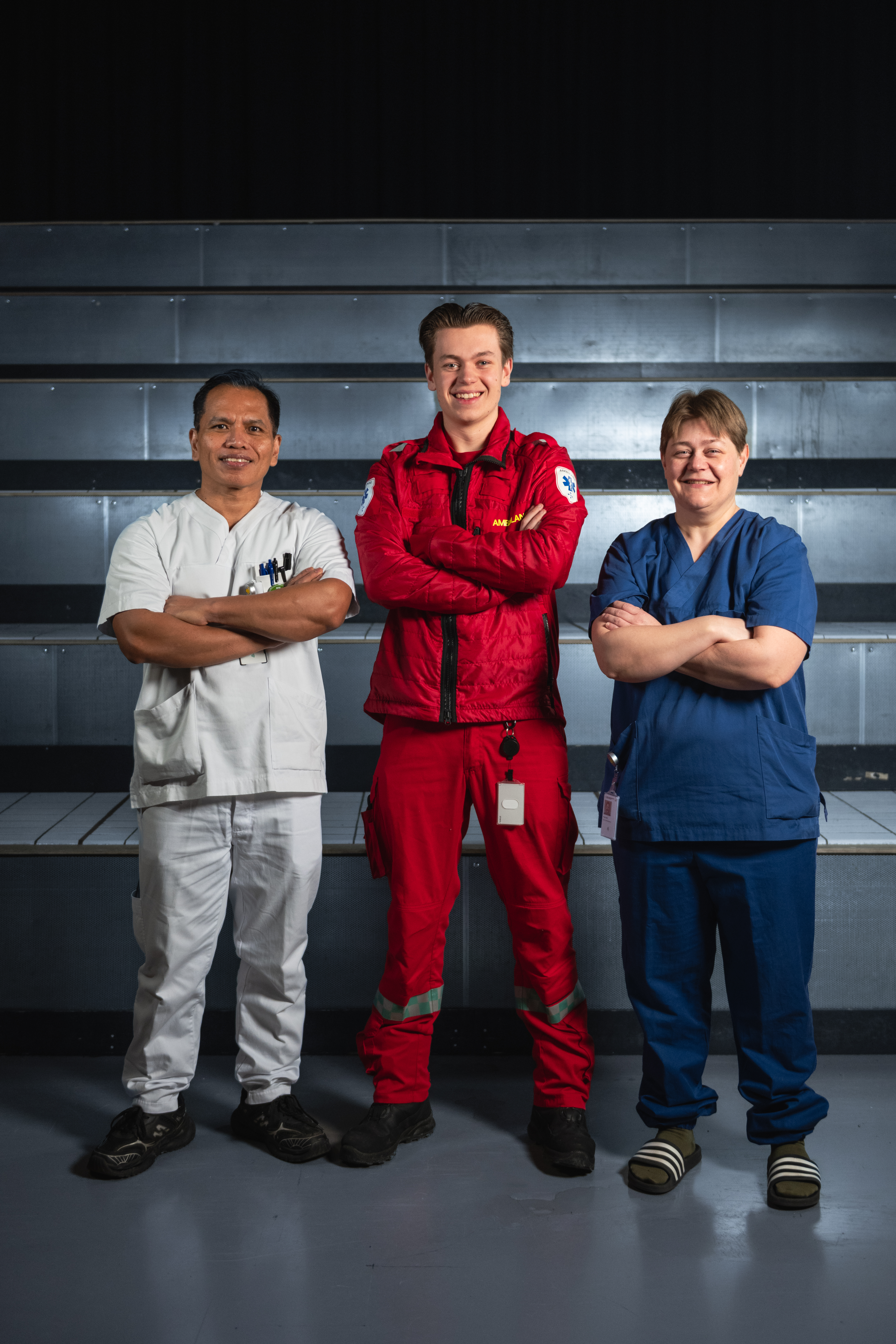 Tre mennesker som står oppstilt med hendene i kryss foran seg