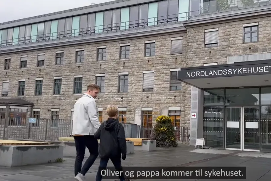 Far og sønn går mot inngangen til sykehus