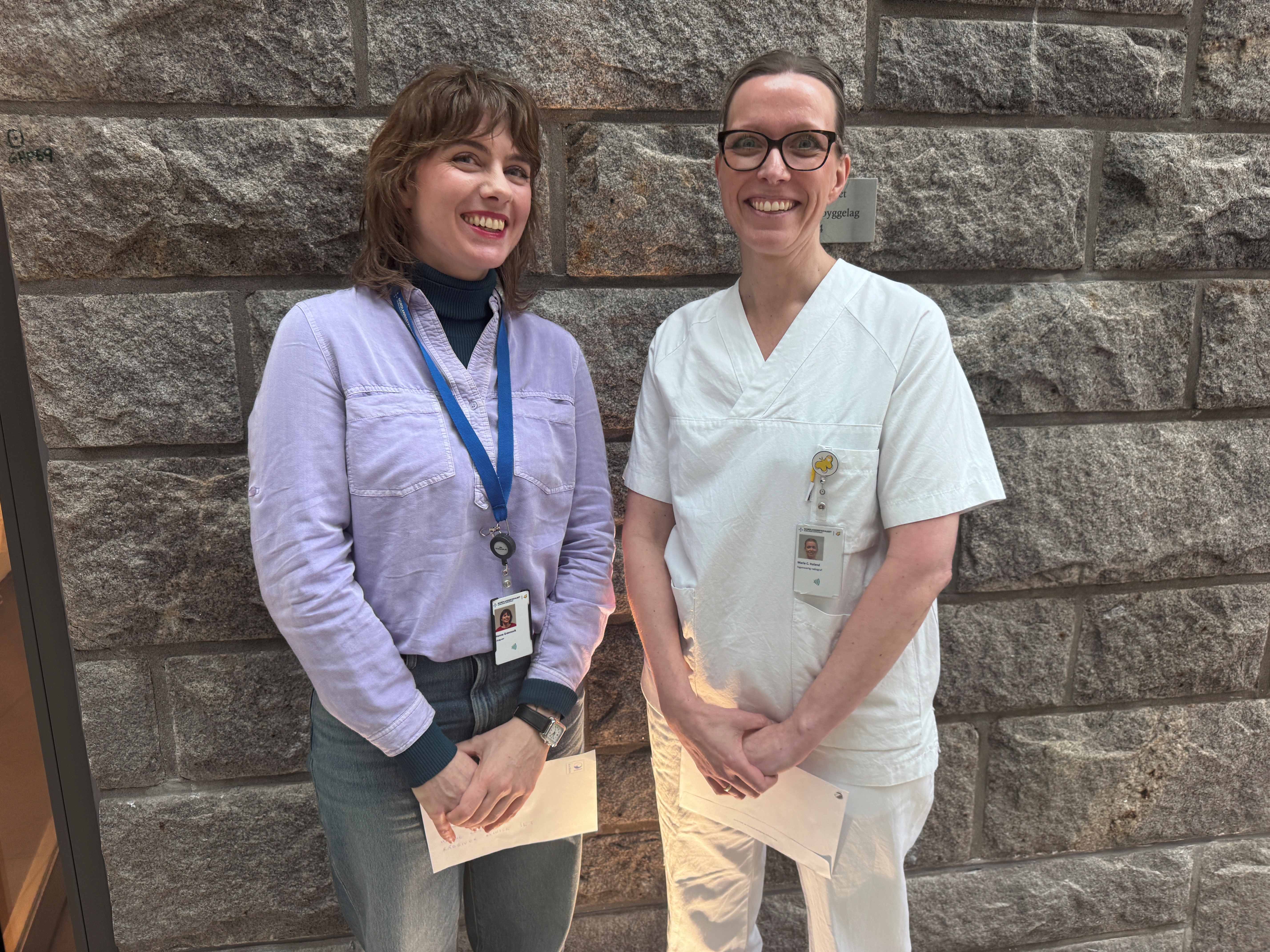 To damer som står samlet og smiler