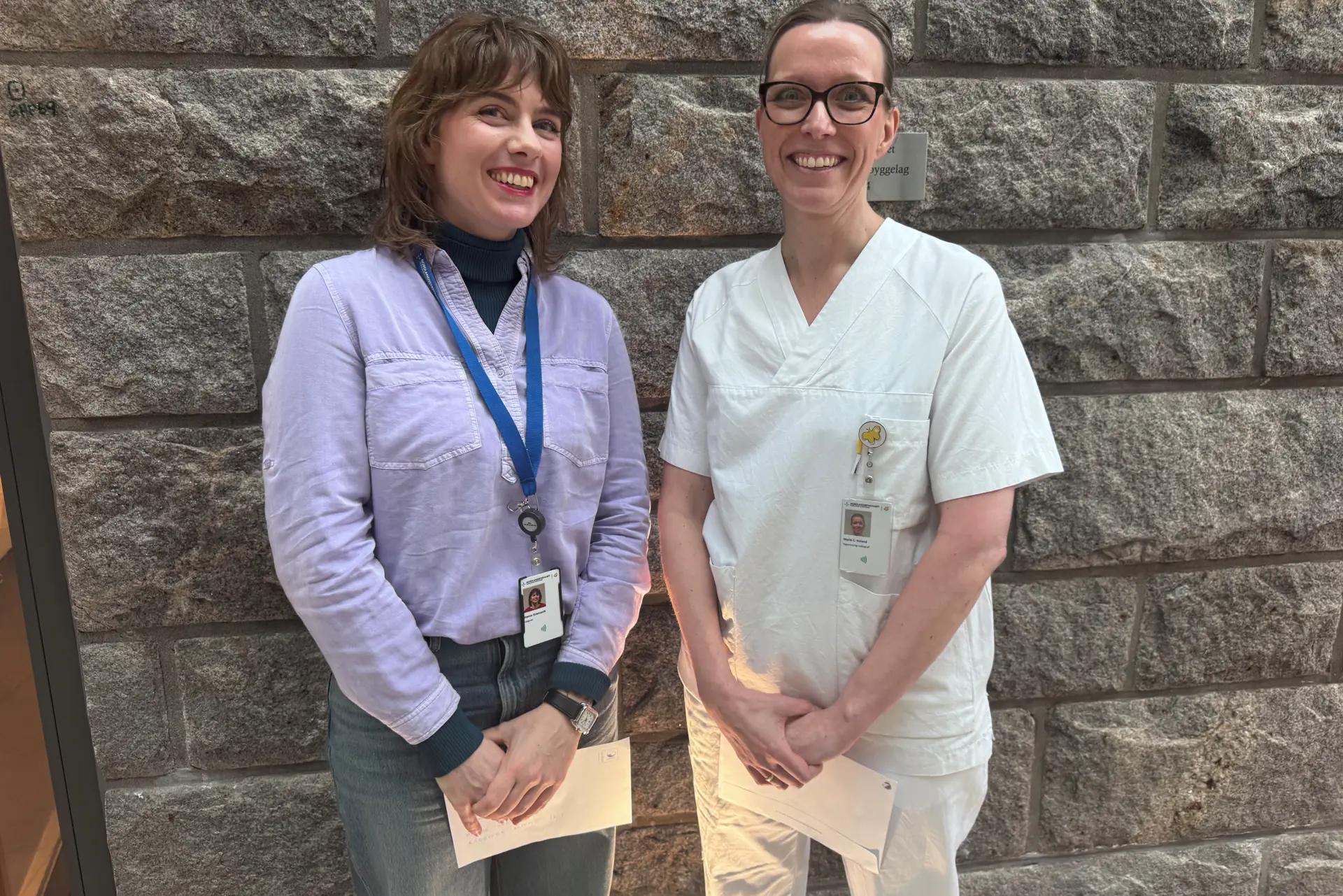 To damer som står samlet og smiler