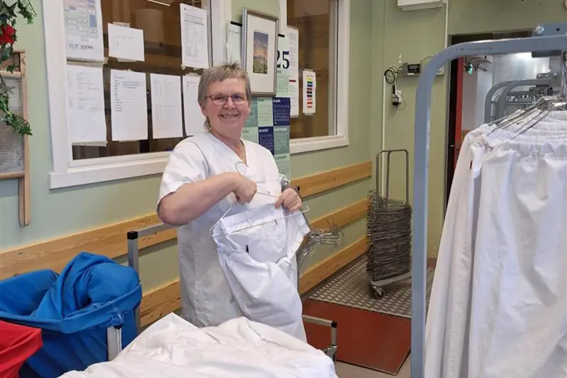 Dame som henger opp klær på stativ