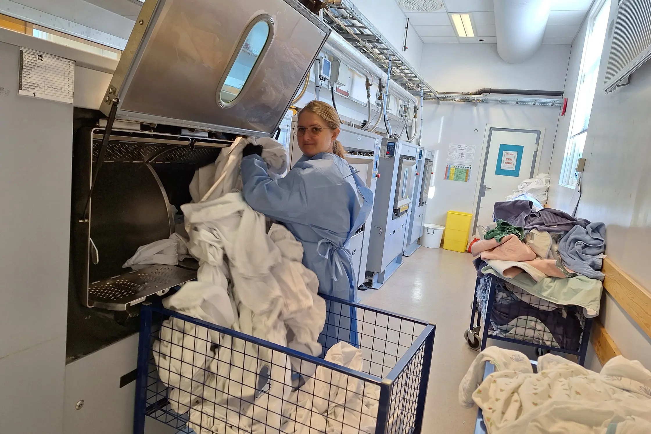 Dame som legger klær inn i en vaskemaskin