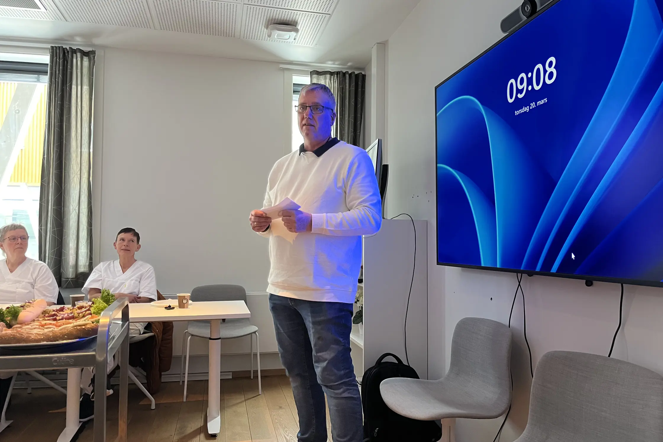 En person som står foran en stor blå skjerm