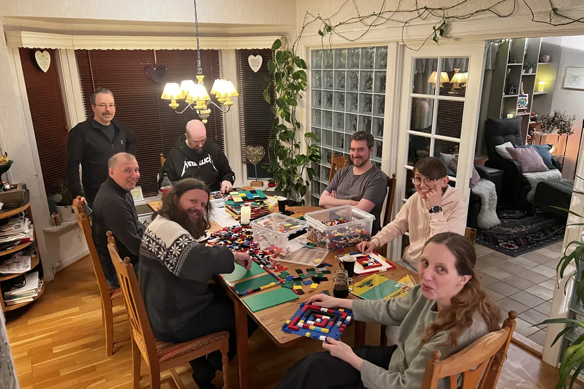 En gruppe mennesker som sitter rundt et bord med lego