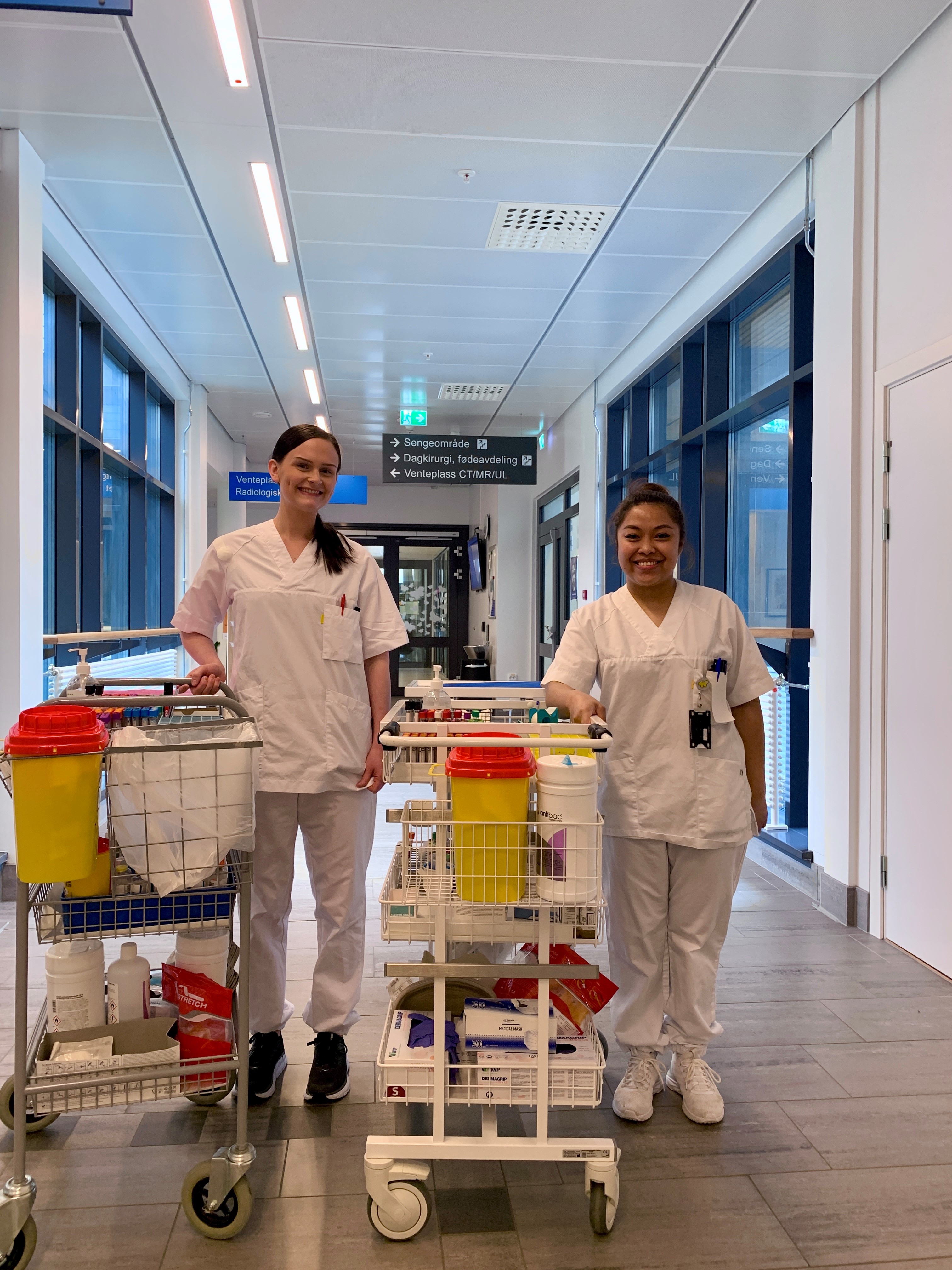 Et par kvinner i hvite frakker med hver sin lab-tralle