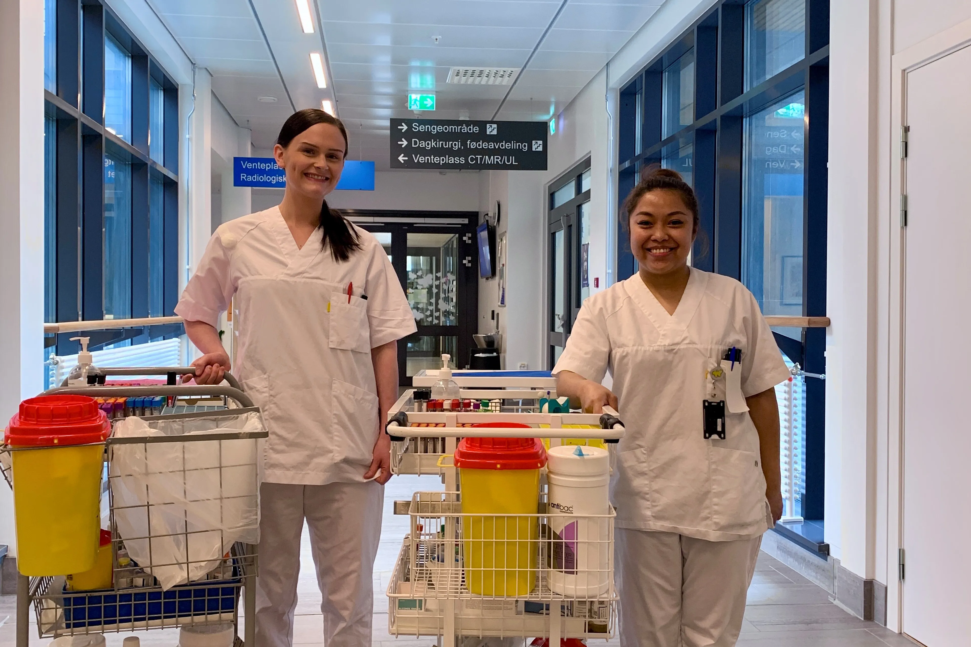 Et par kvinner i hvite frakker med hver sin lab-tralle