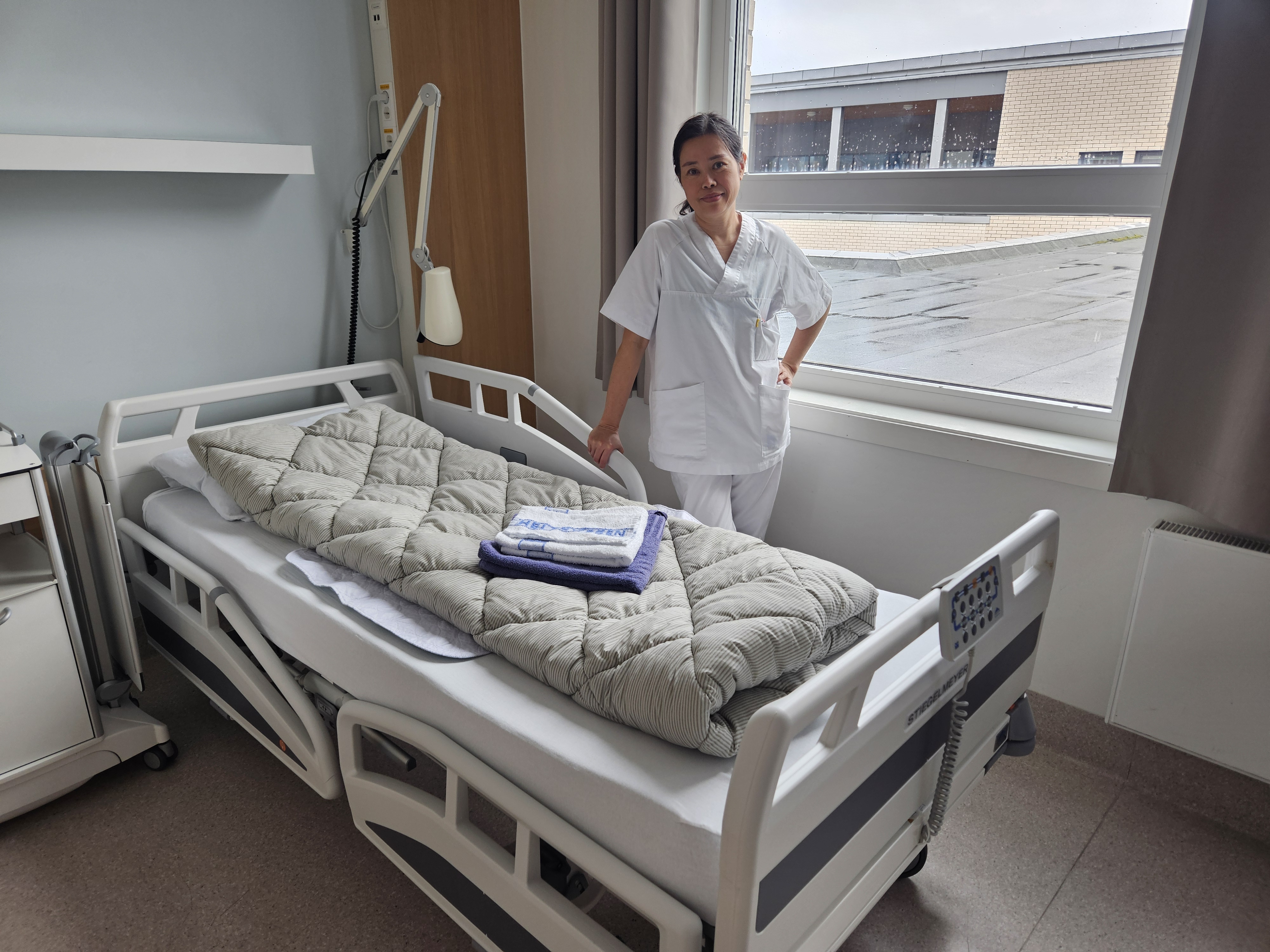 En person som står ved siden av en seng