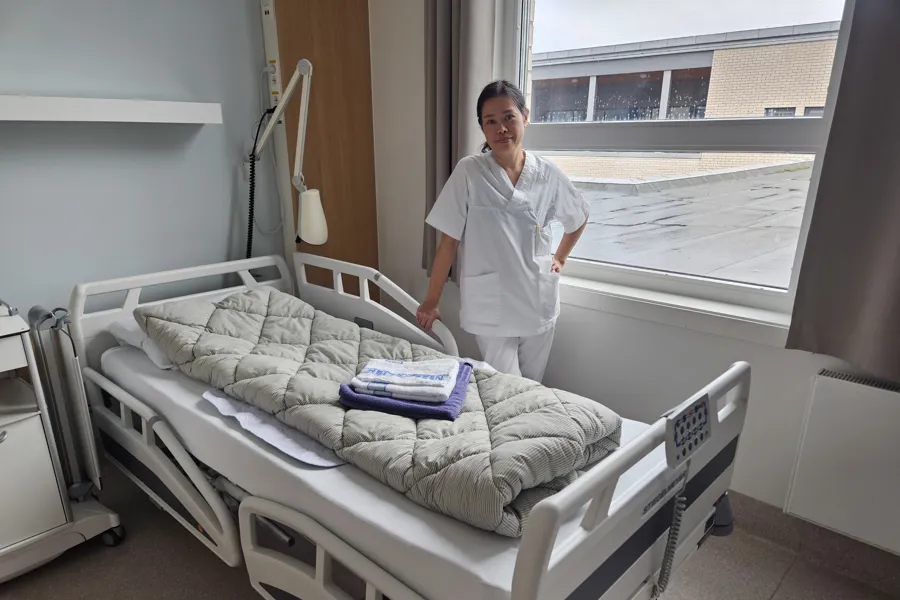 En person som står ved siden av en seng