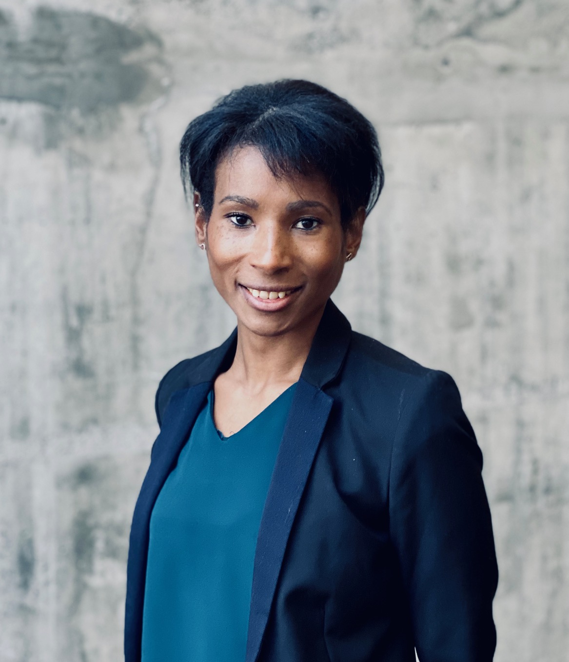 En person som smiler foran en hvit vegg