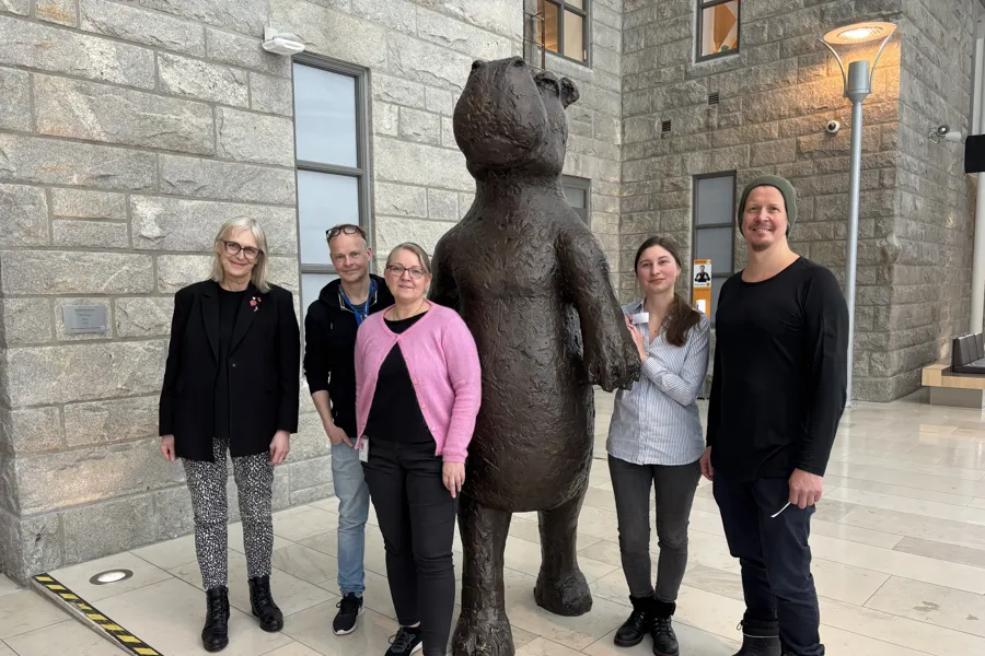 Fem personer som står samlet atmed en statue