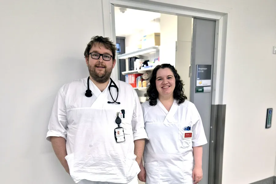 En mannlig og kvinnelig sykepleier som står samlet og smiler