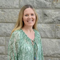 A woman smiling in front of a stone wall
