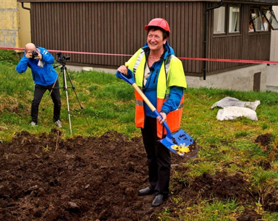 En person som holder en spade og et kamera