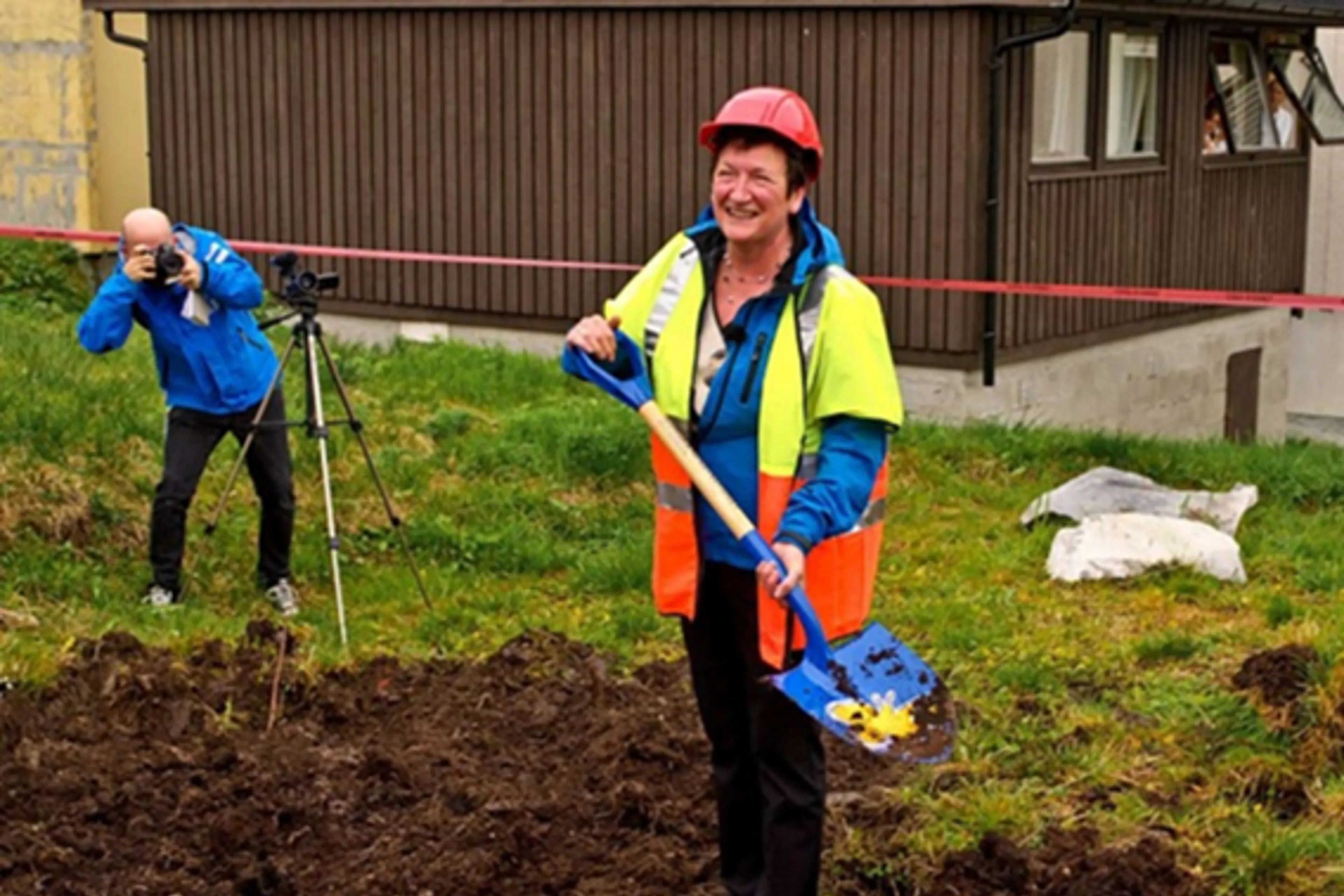 En person som holder en spade og et kamera