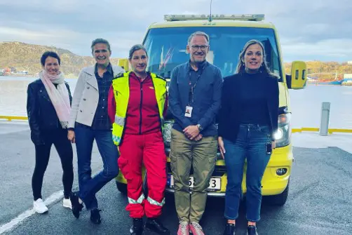 En gruppe mennesker som poserer for et bilde foran en blå lastebil