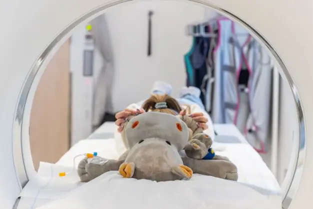 En bamse som ligger på en seng som er inni en røntgenmaskin
