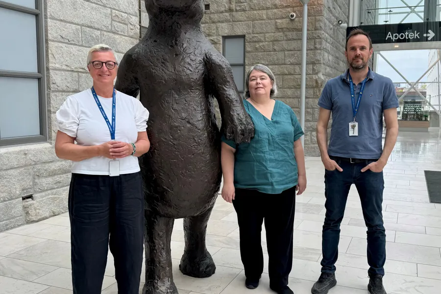 En gruppe mennesker som poserer for et bilde ved siden av en statue