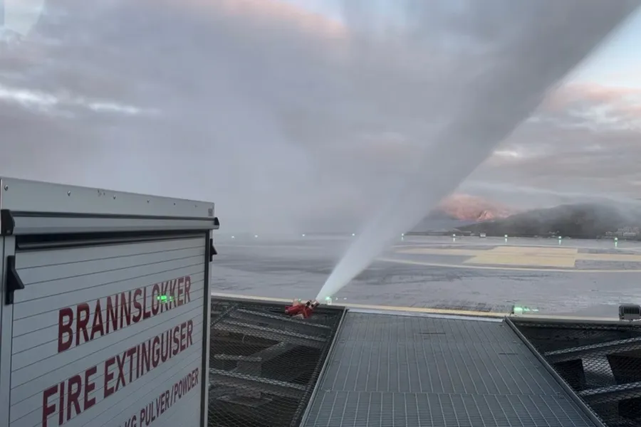 Brannslange som spruter vann på et helikopterdekk. Mye røyk