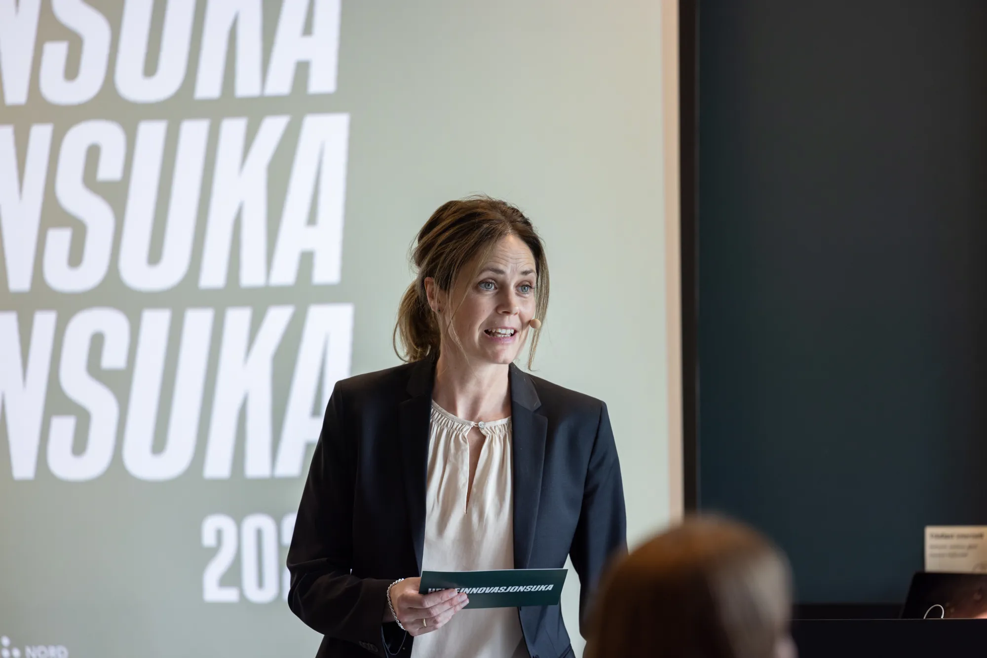 Dame som står foran en skjerm med tekst