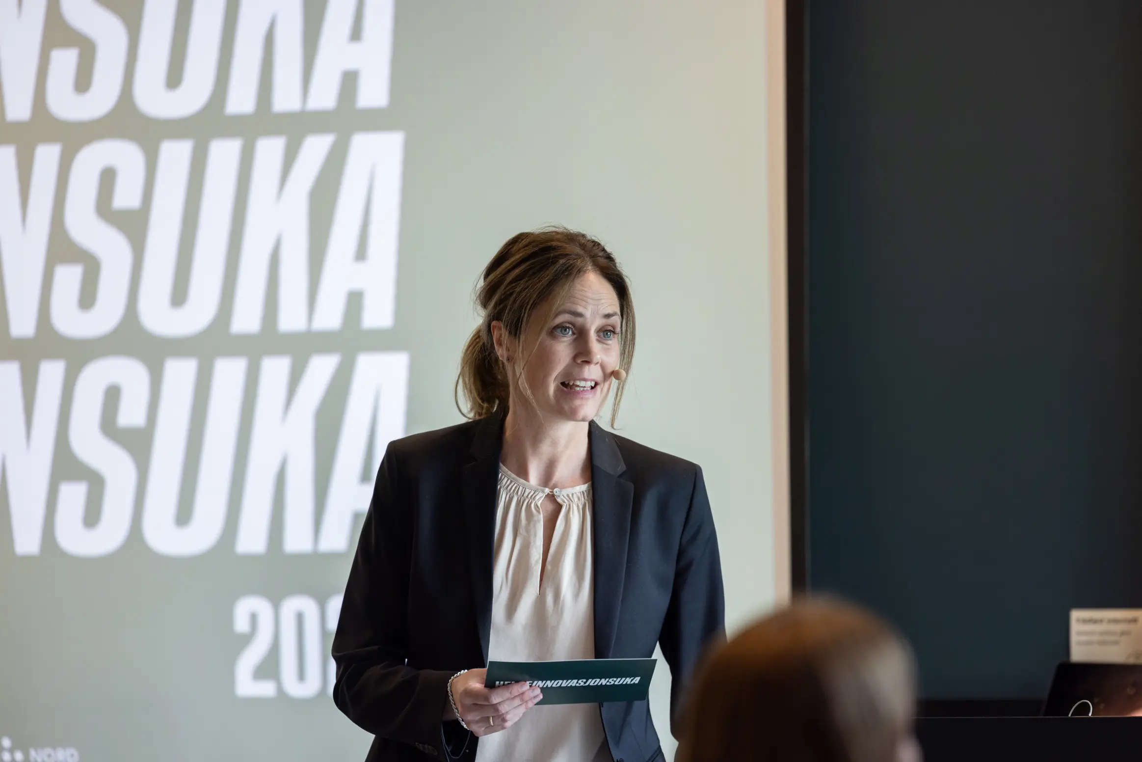 Dame som står foran en skjerm med tekst