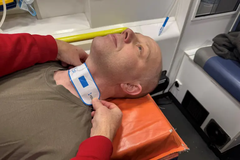 En person som ligger og får et plaster på halsen