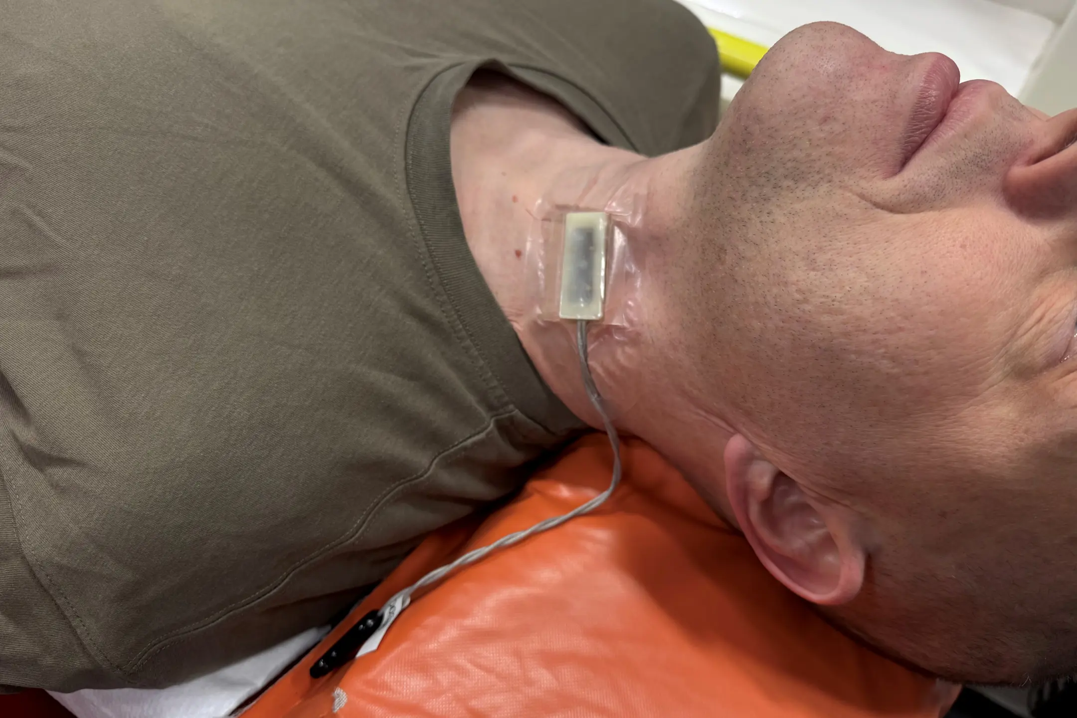 En mann som ligger med plaster på halsen