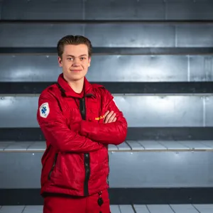 Ung mann i røde ambulanseklær med henda i kryss