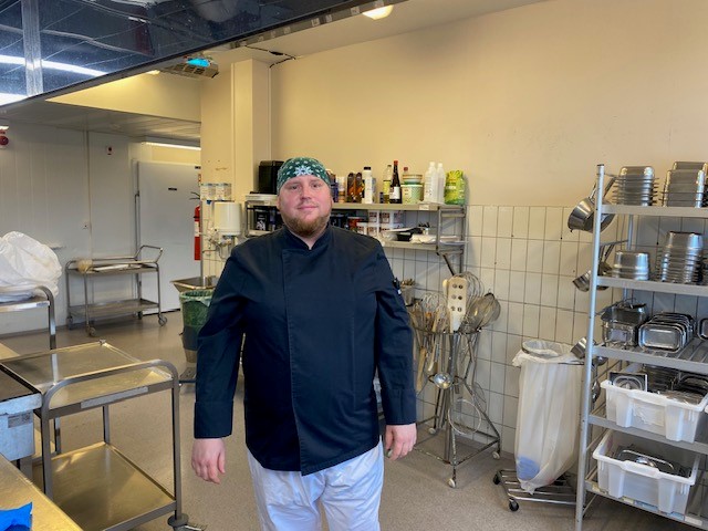 En mann som står i et rom med hyller og et bord