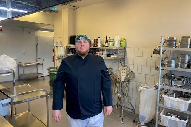 En mann som står i et rom med hyller og et bord