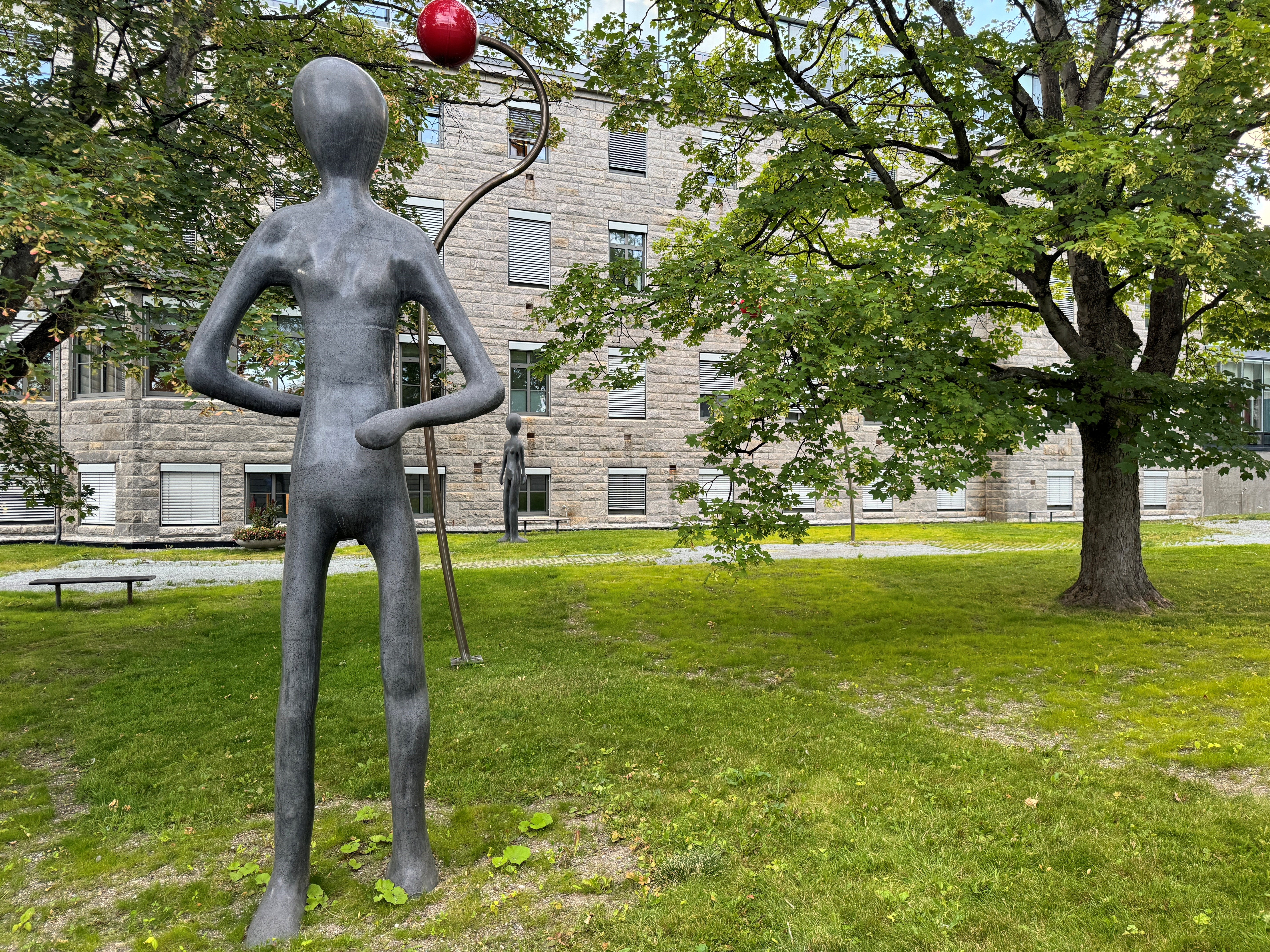 Statuer og trær i en park med grønt gress