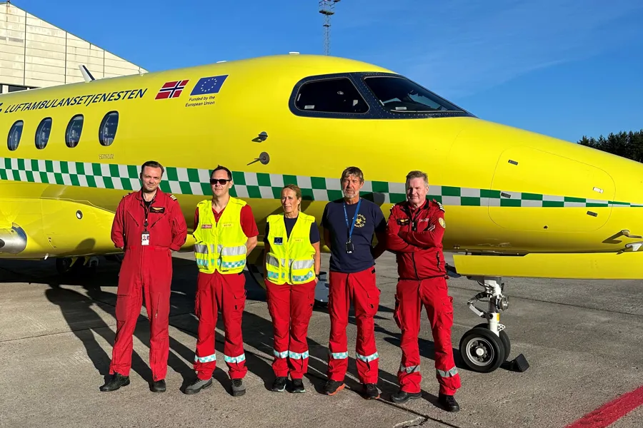 En gruppe mennesker foran et gult og blått fly