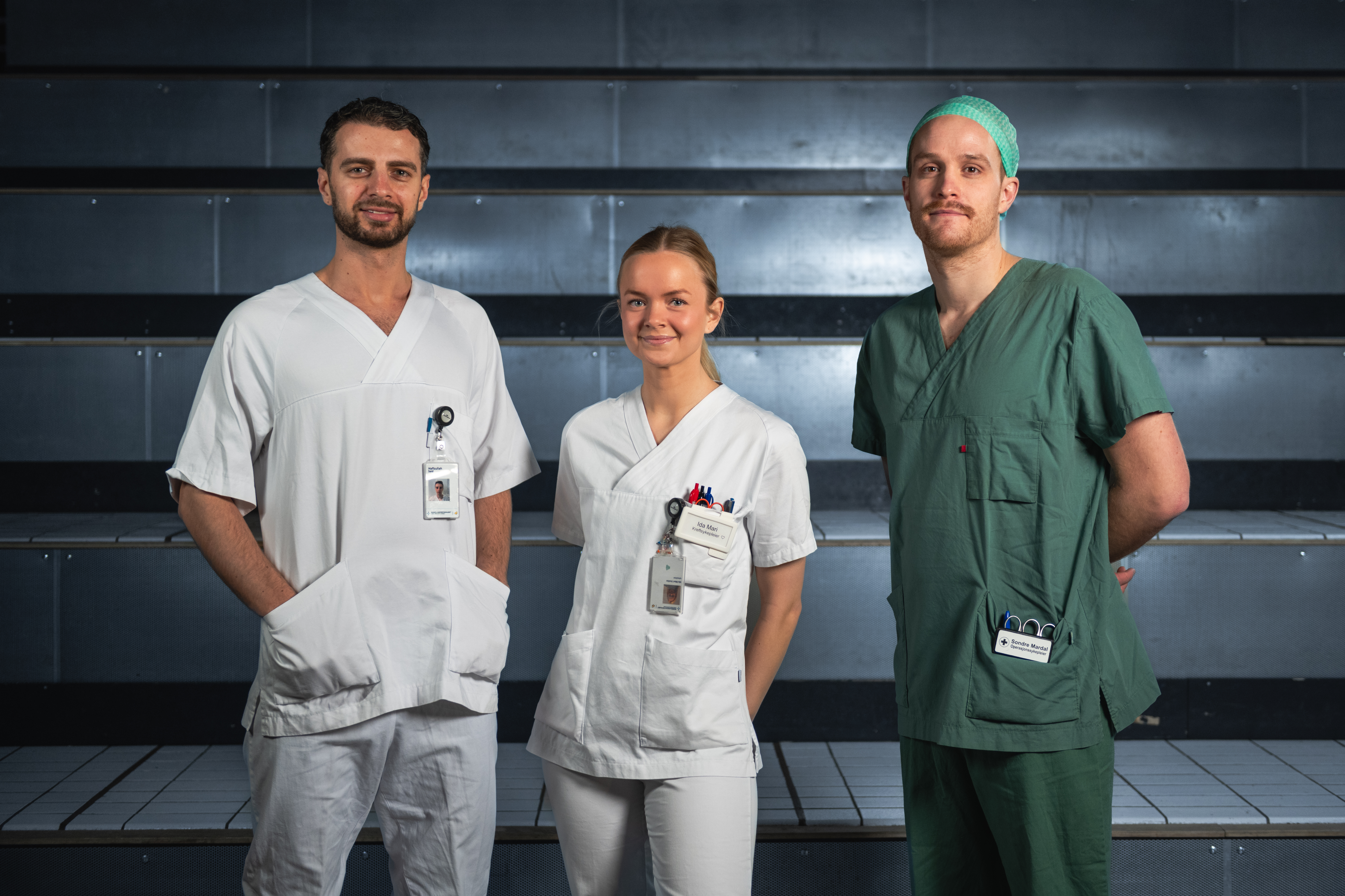 Tre personer som står oppstilt og ser mot kamera