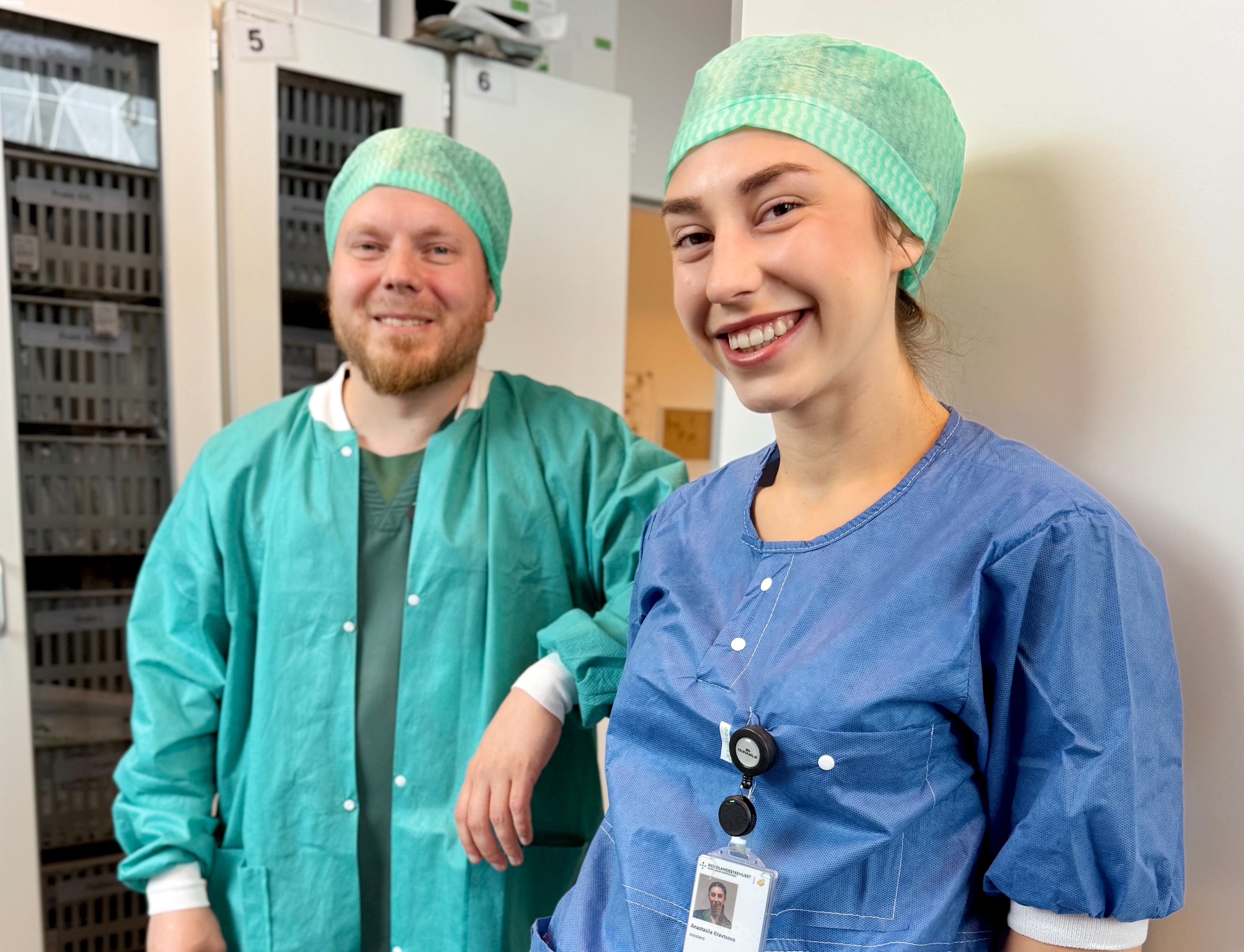 En mann og en kvinne med grønne opersjonshatter som smiler