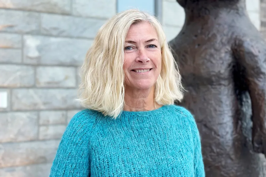 En kvinne som smiler ved siden av en statue