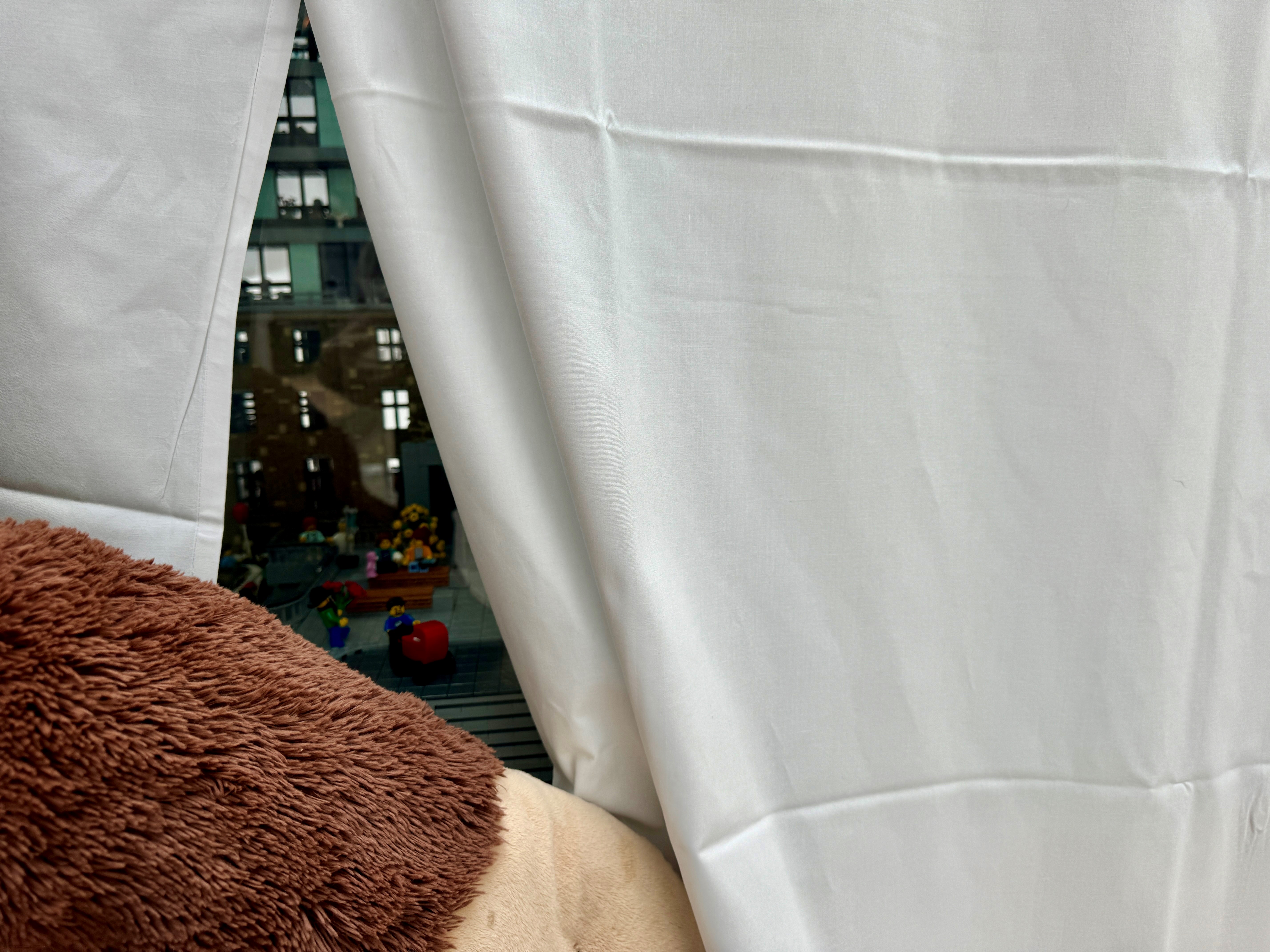 En hvit gardin med utsikt over en gate og bygninger