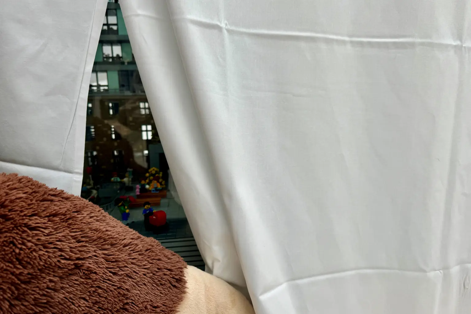 En hvit gardin med utsikt over en gate og bygninger