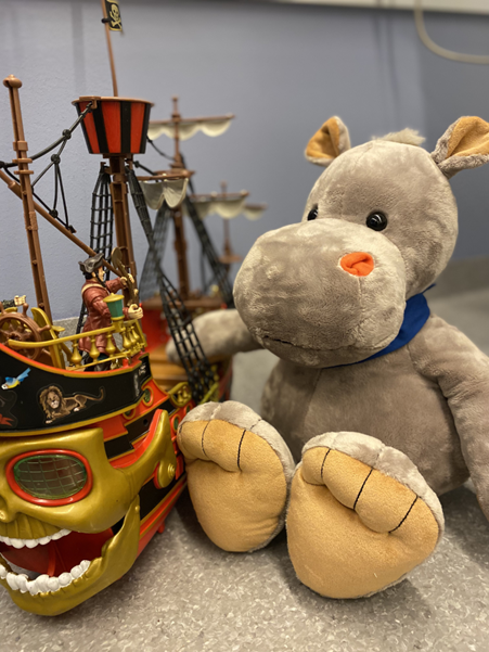 En teddybjørn som sitter ved siden av en lekebåt