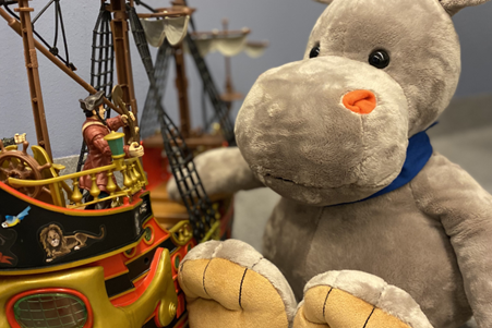 En teddybjørn som sitter ved siden av en lekebåt