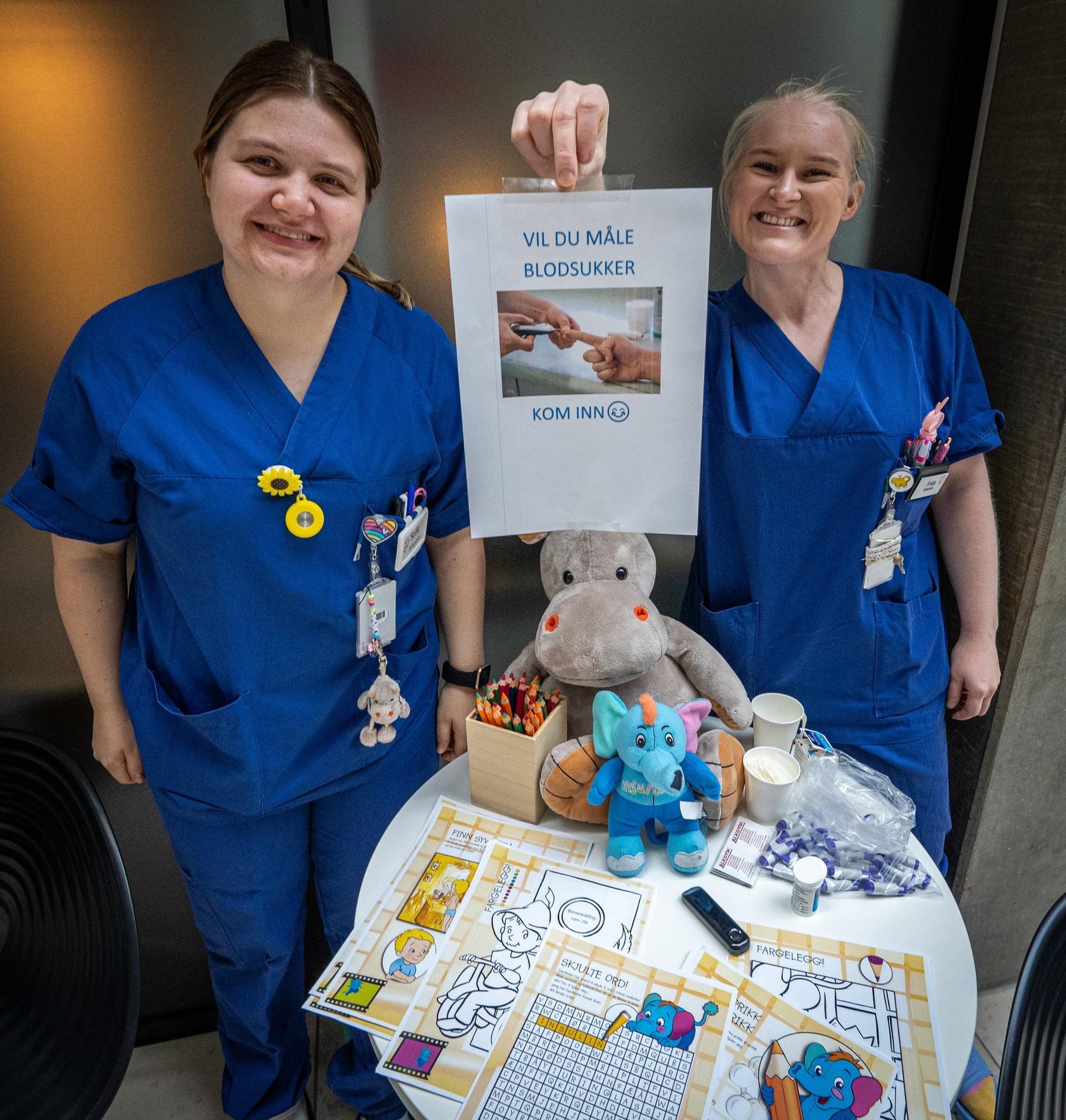 Kvinner som står ved siden av et bord med en bamse og et skilt